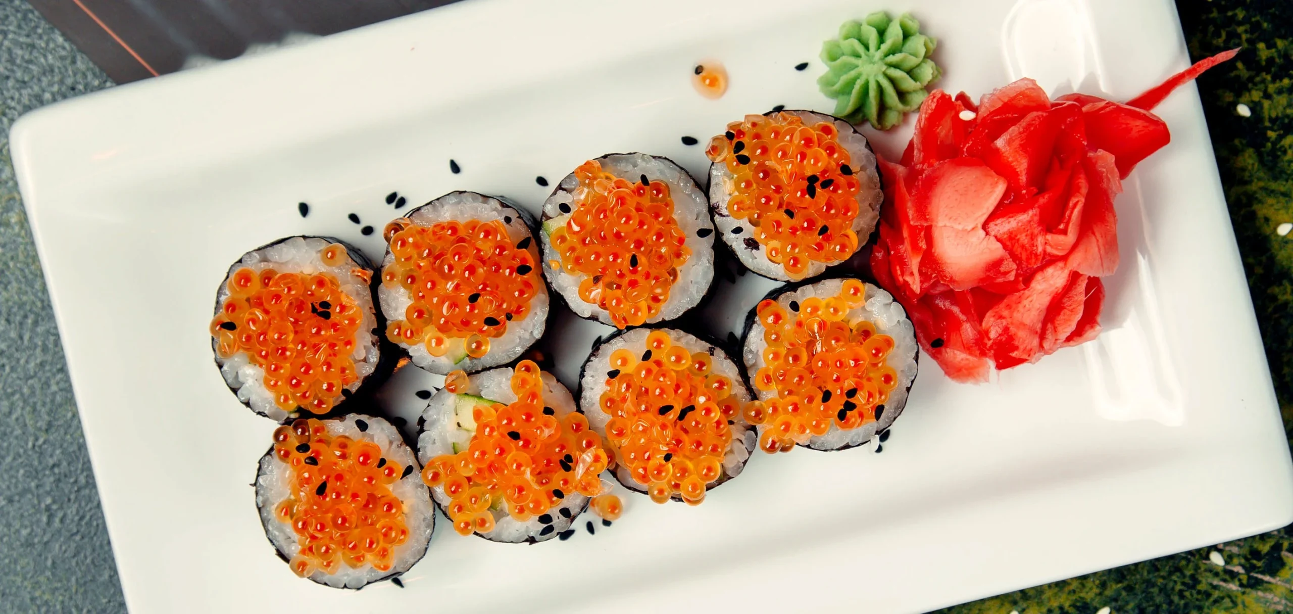 Tobiko, bright orange fish roe, sprinkled on top of sushi rolls